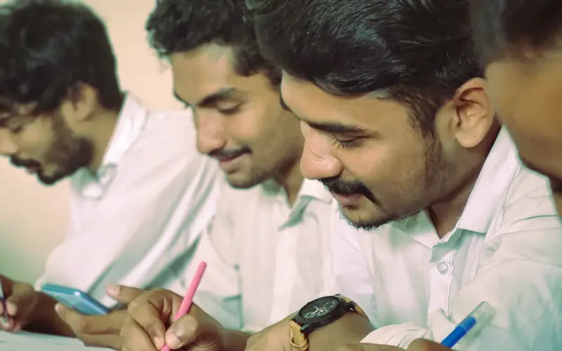 Three students working together over a notebook