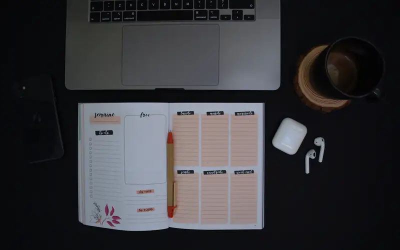 A weekly planner open on a dark desk
