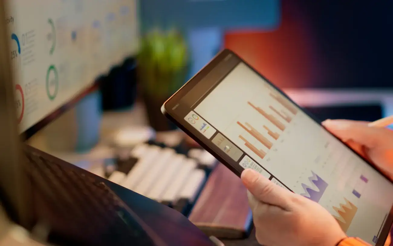 A tablet showing bar charts, held over a desk