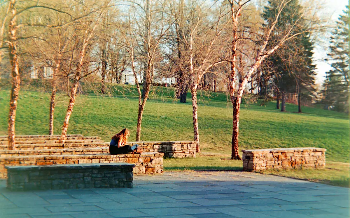 A student sitting alone on a campus lawn