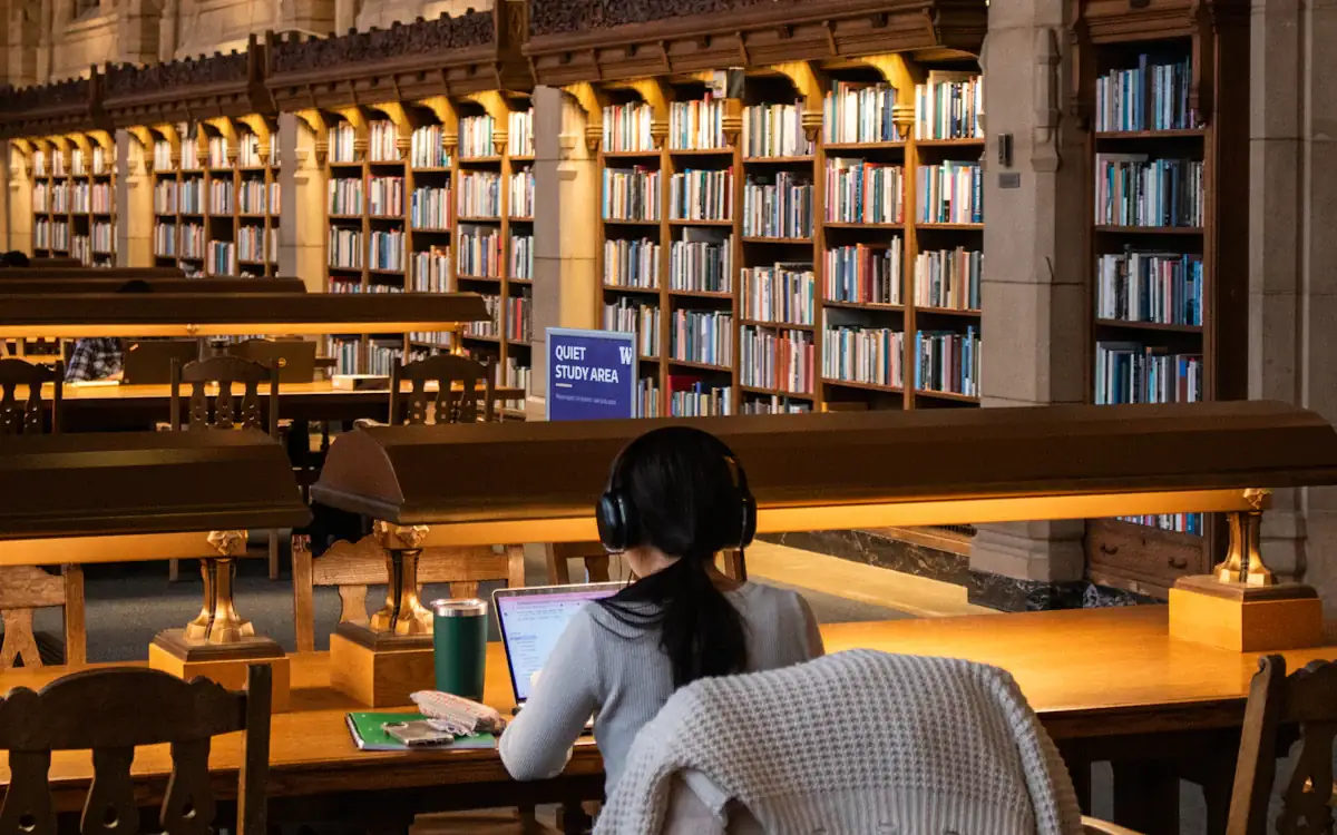 A student at a desk in a warmly lit library